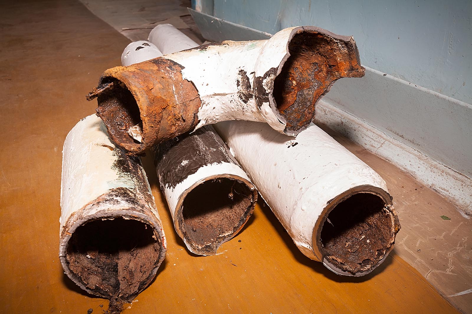 Fragments of an old pipe. Apartment in a multi-storey residential building in the city. Several pieces of piping are on the floor. Color photo.