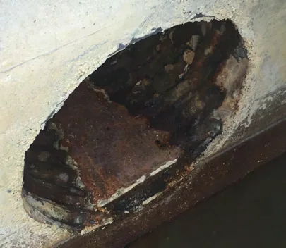 Rusted interior of the 24-inch FPL corrugated-metal drain with a hole through its wall, before lining